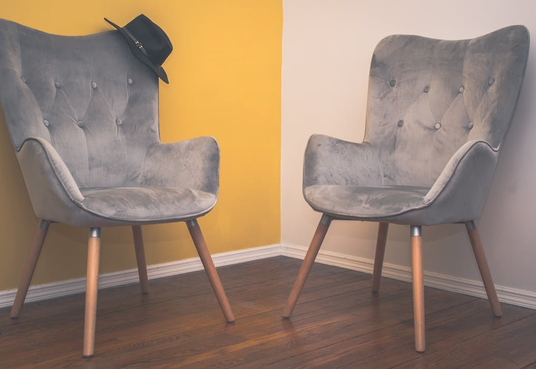 two suede sofas on a brown hardwood floor against a wall