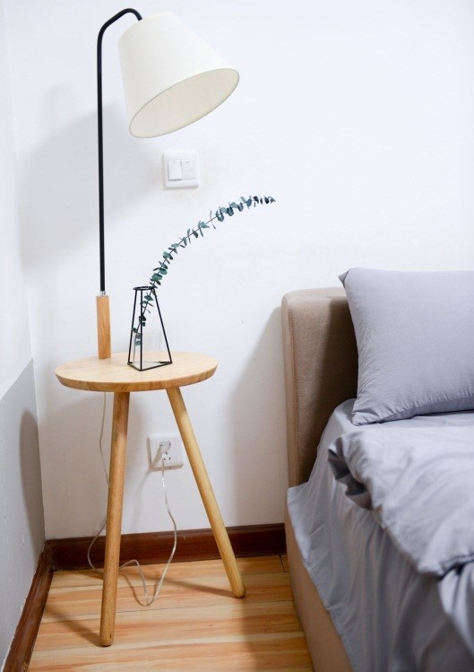 bed and a lamp table on a light wood floor