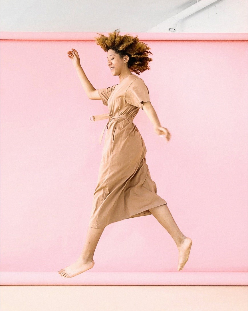 women jumping in front of a pink wall