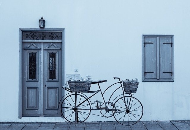 House front with a gray wall and a bicycle.