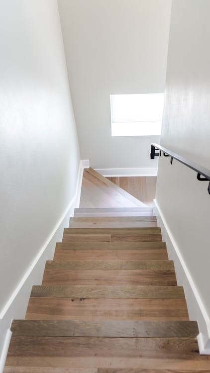 The top stair view of a wood staircase and white walls.