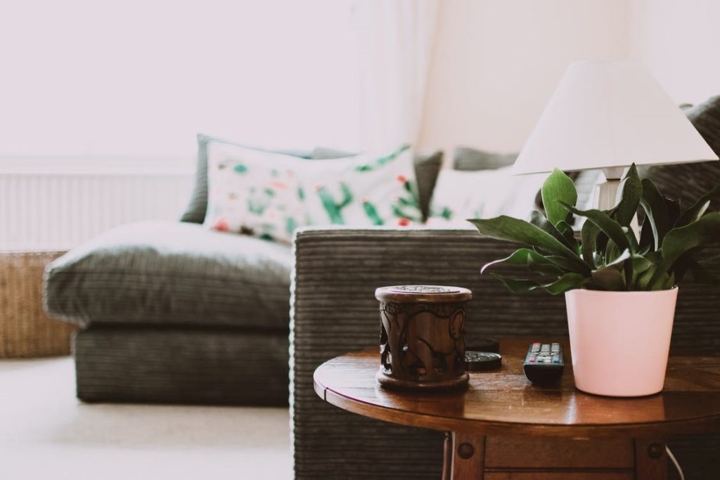 A textured sofa next to a table with a plant on it.