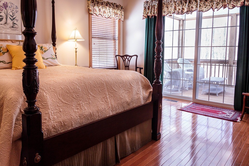 A bedroom with a gorgeous, shiny hardwood floor and balcony