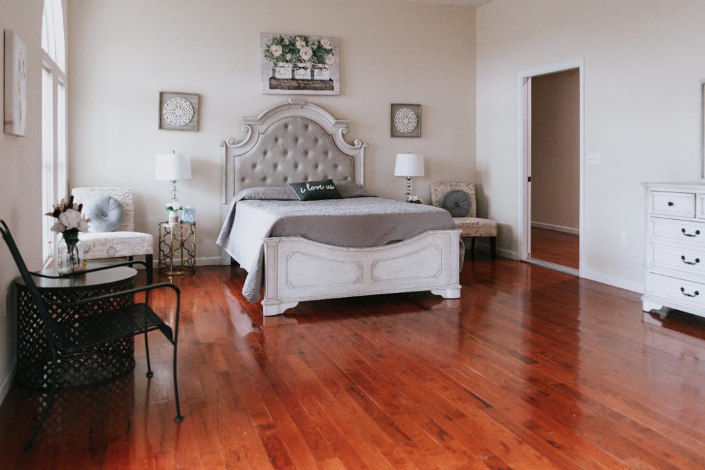 A white bed placed in a bedroom with hardwood floors