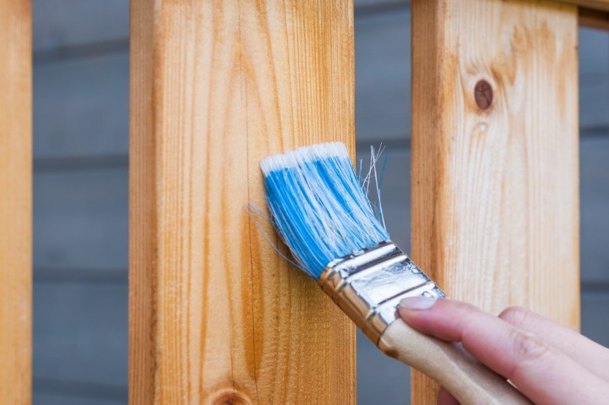 A carpenter applying finished on wood before installing it as flooring