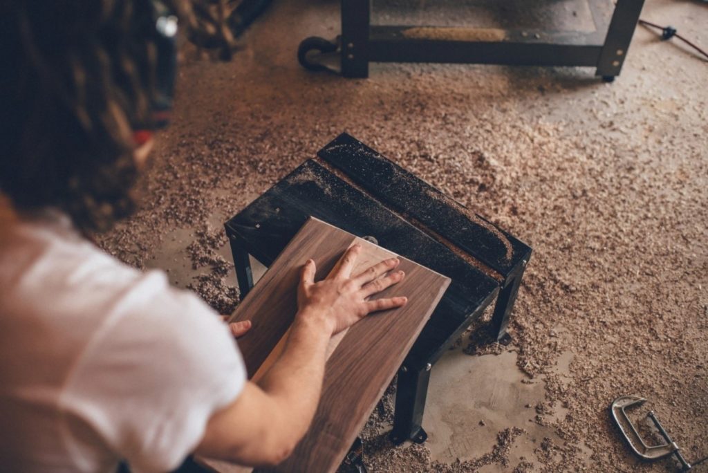 Alt-Text: A worker working on a plank of wood in the workshop