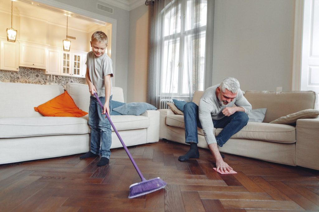 Grandfather and grandson cleaning hardwood floor