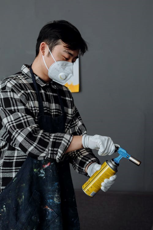 a man wearing a mask while spraying chemical