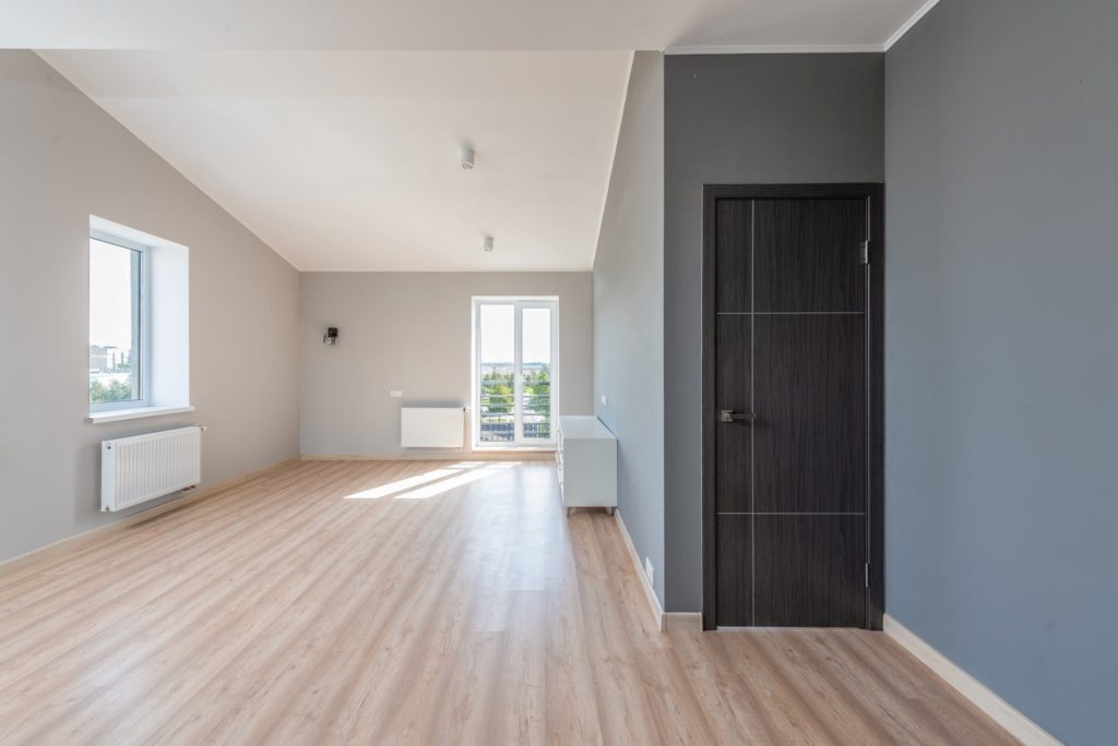 a room with a clean wood floor and two windows