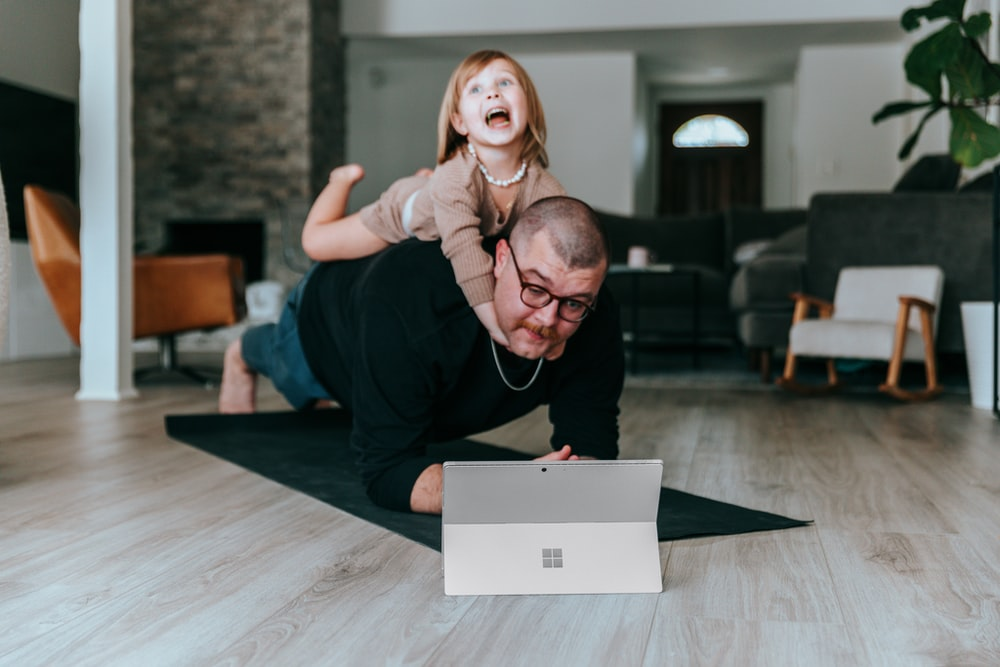 A father and daughter playing on a hardwood floor.