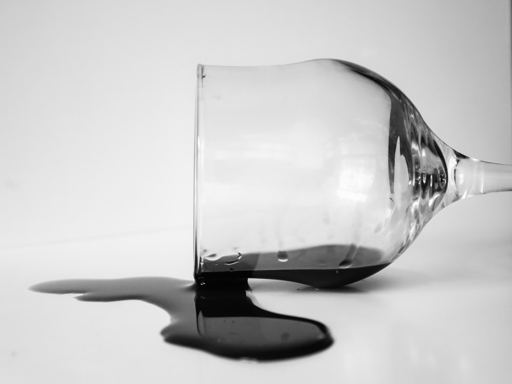 A champagne glass spilling a dark-colored drink