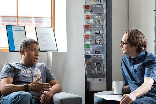 Two men talking beside a magazine stand