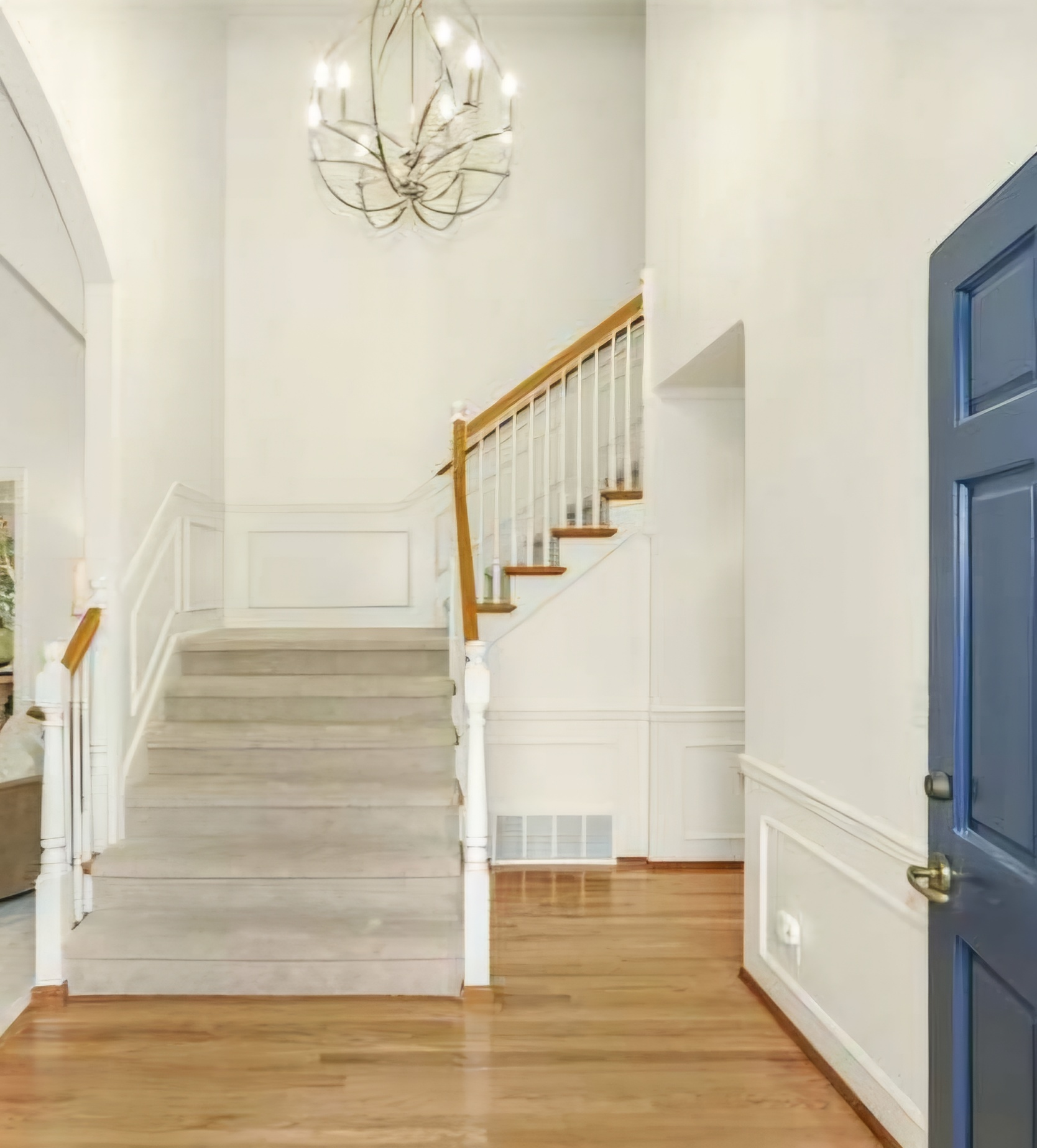  an entryway with light hardwood flooring, a staircase, and a blue front door